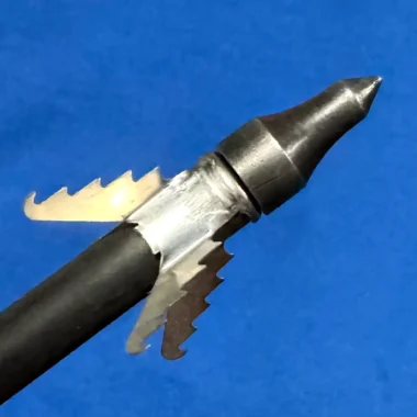 Broadhead hunting arrow tip with sharp metal blades, close-up against blue background
